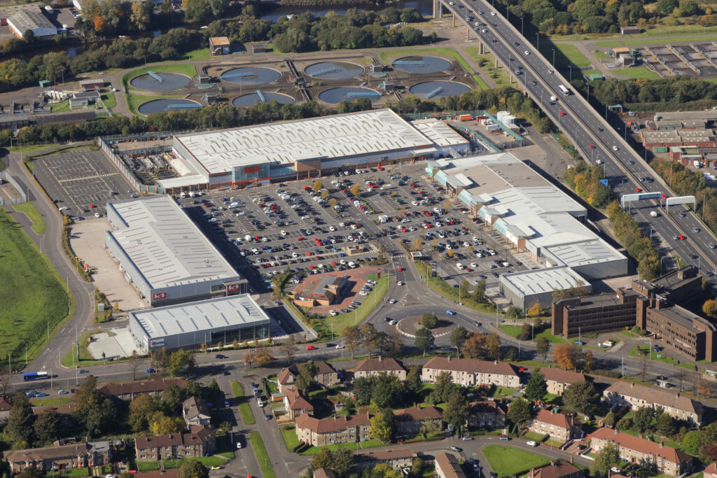 Aerial view of Abbotsinch Shopping Park and its car parks, with the surrounding motorway and residential streets