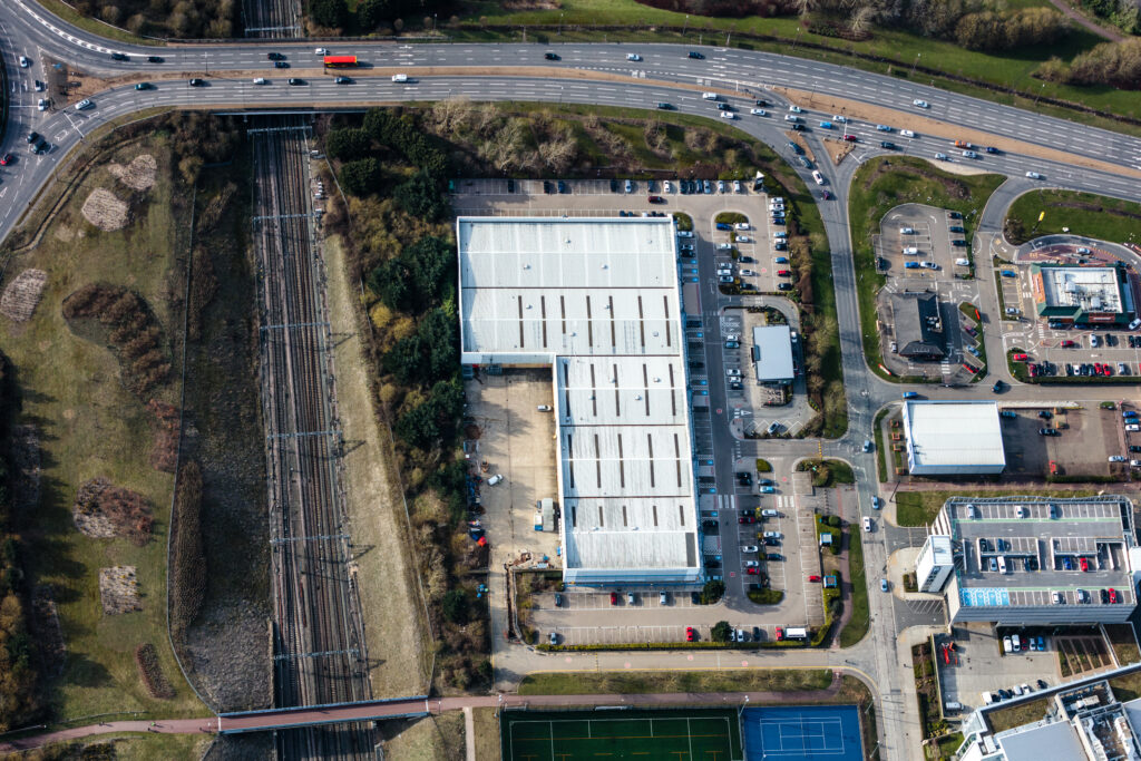 Aerial view of a retail warehouse building beside a motorway junction at The Place Retail Park
