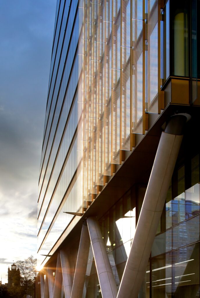 Exterior corner of Moor Place, 1 Fore Street, London EC2, with angled concrete columns and pedestrians
