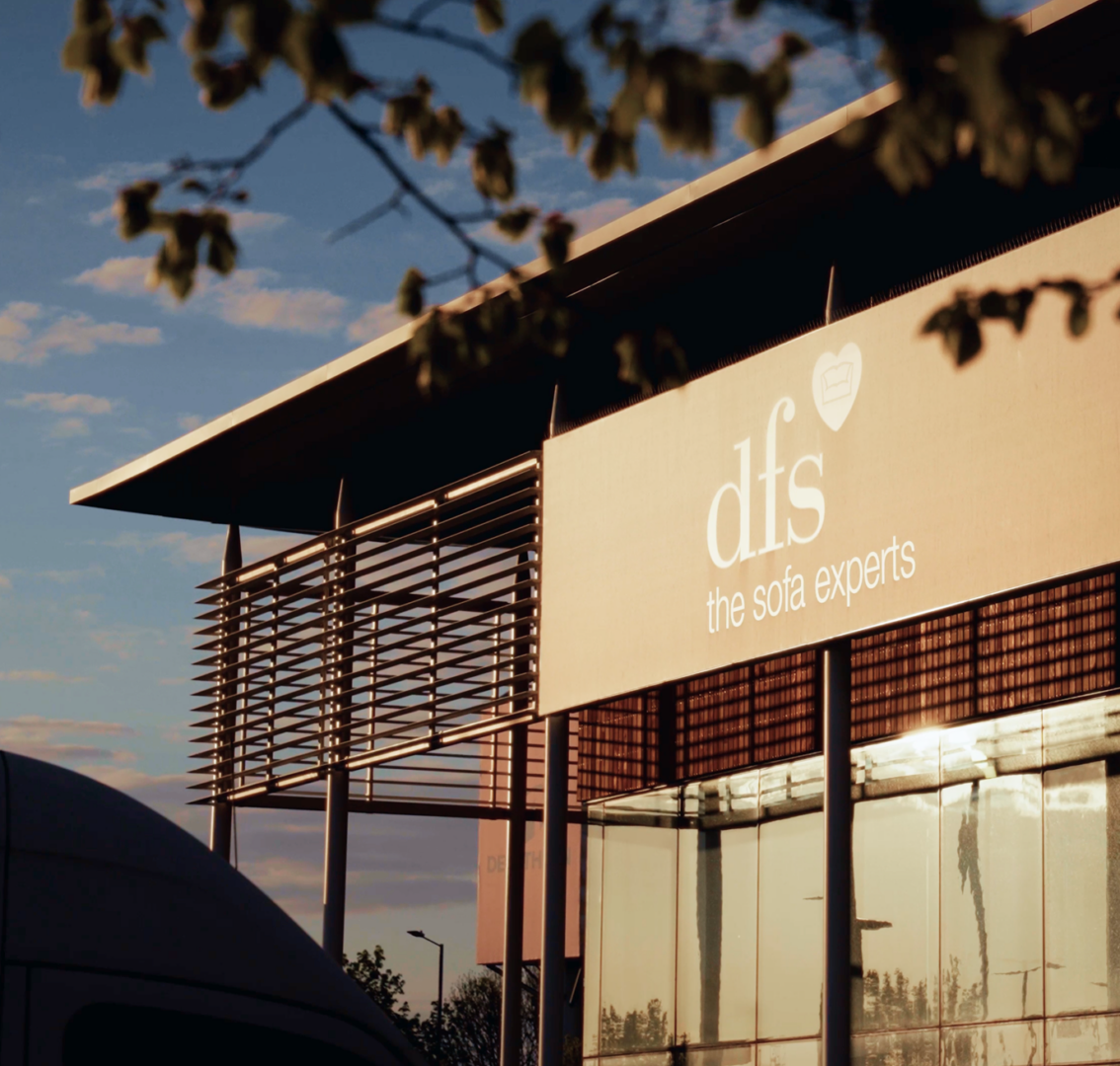 DFS retail unit signage reading 'the sofa experts', silhouetted against an evening sky through branches