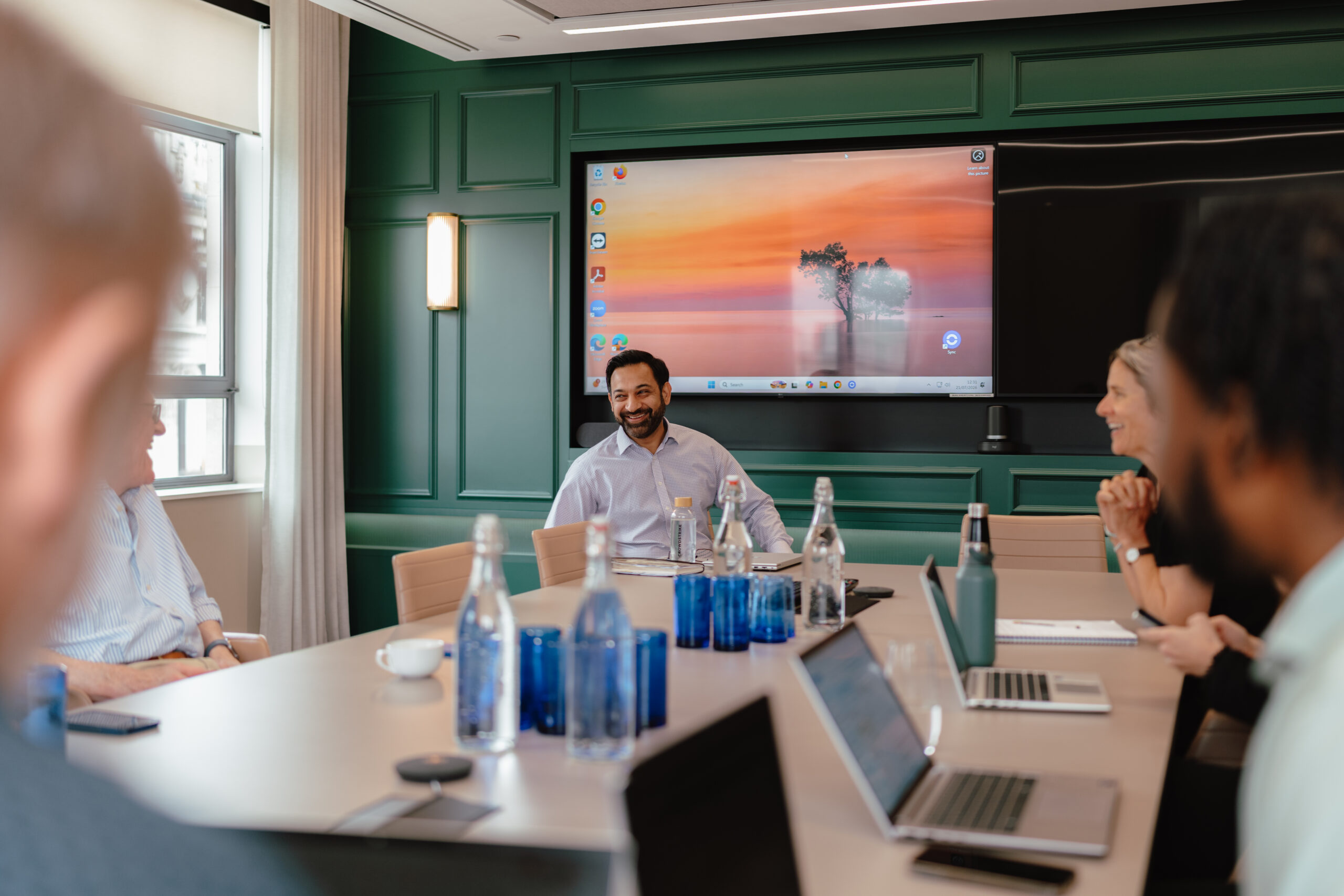 Colleagues laughing during a presentation in the Quadrant boardroom